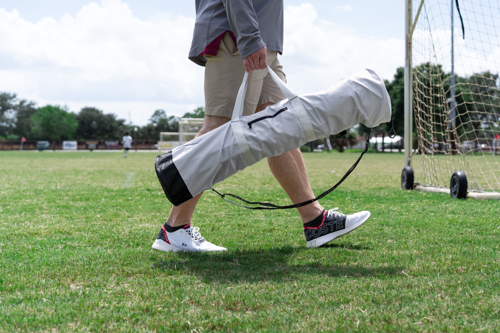 A FieldLux founder carrying the chair bag along a soccer field sideline.